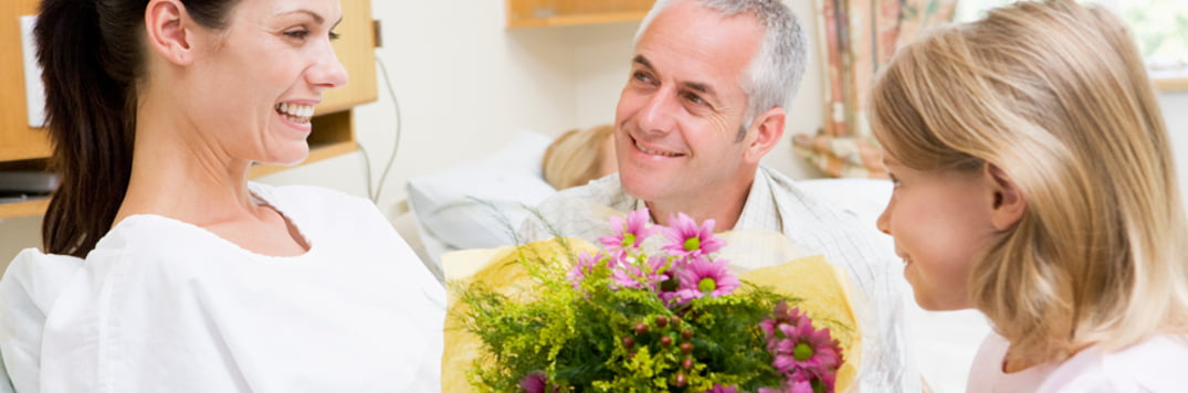 Happy family gathered around hospital bed.