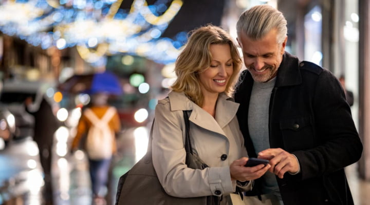 Happy couple on city street looking at smartphone